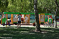 Tramwajowy plac zabaw - zabawka imitująca tramwaj, wewnątrz bawiące się dzieci a w pobliżu dorośli