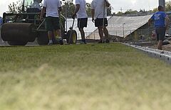 Pracownicy układają trawę z rolki na stadionie miejskim w Olsztynie