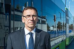 Prezydent Olsztyna w garniturze na tle olsztyńskiego tramwaju