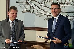 Dyrektor firmy Skanska i prezydent Olsztyna po podpisaniu umowy wymienili się dokumentami
