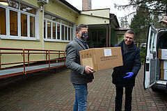 Przekazanie kartonu ze strzętem, w tle samochów