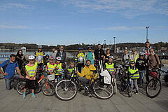 Rowerzyści pozują do zdjęcia nad brzegiem jez. Krzywego.