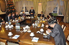 Spotkanie polskiej i chińskiej delegacji, goście siedzą przy stole, na stojąco przemawia prezydent Olsztyna Piotr Grzymowicz